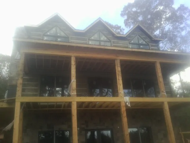 Dormers and porch framing on a large log home under construction — Roof Coating work by our crew in Pittston