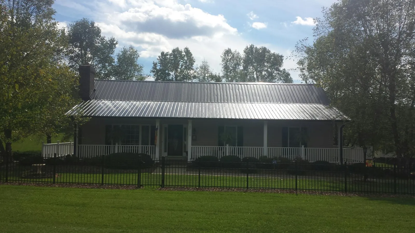 Gray metal roof on a brick ranch with a full width front porch — Gutter Guard Installation work by our crew in Pittston