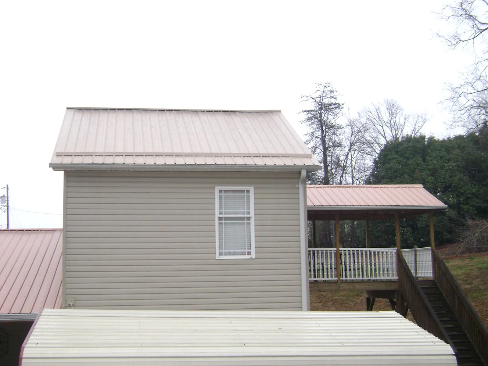 Tan metal roofs on a two story addition and attached porch, from a Roof Replacement job in Pittston
