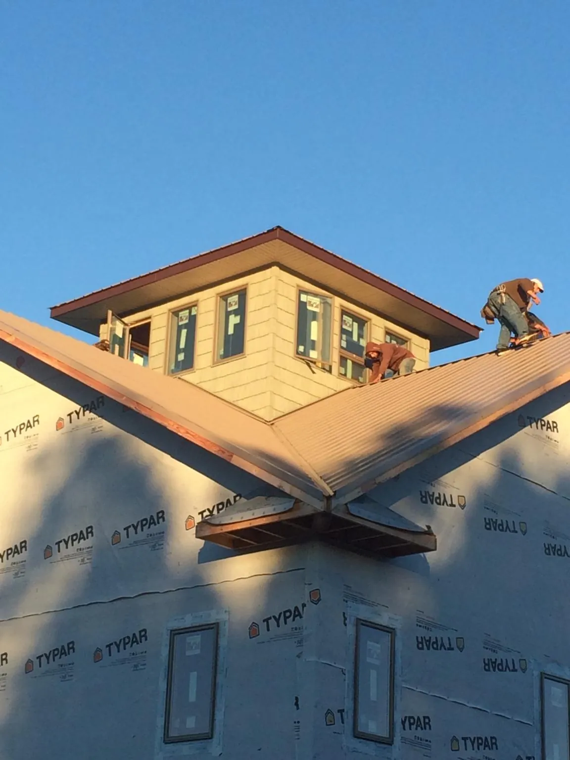 Roofers working around a rooftop cupola on a new metal roof at sunset — Roof Waterproofing in Pittston by Roofing Brothers
